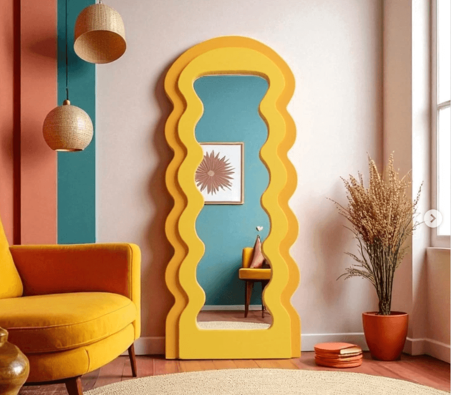 Full-length wavy arch floor mirror in bright yellow, with a scalloped rippled frame, leaning against a wall in a colourful living room